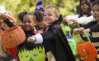 Crianças estendem suas sacolas para ganhar doces, durante festas do Halloween.