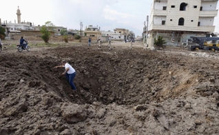 Homem sai de uma cratera causada pelo que, segundo ativistas, foi aberta pelo lançamento de bombas das forças leais ao presidente da Síria, Bashar Al-Assad. (Foto: Reuters)