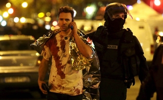 Policial acompanha vítima do ataque à casa de shows 'Bataclan', em Paris. (Foto: Reuters)