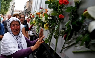 Uma mulher chora ao lado de um caminhão que transportava 136 caixões de recém-identificadas vítimas do massacre de Srebrenica, em 1.995 (Foto: Reuters)