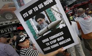 Mulher segura placa em protesto contra o acordo nuclear entre as potências mundias e o Irã. (Foto: Mike Segar / Reuters)