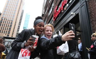 A jovem Jaimie Cranford (à direita) tira uma selfie com Mariah Reives (esquerda), exibindo sorrisos e seus lanches da rede lanchonetes fundadas por cristãos. (Foto: Tina Fineberg / AP Photo)