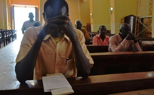 Cristão sudanês ora dentro do templo de igreja. (Foto: La Stampa)