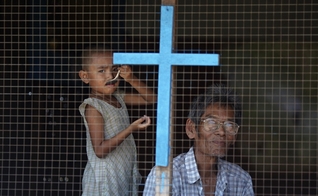 Homem e criança de família cristã olham pela janela de sua casa nos subúrbios de Yangon, em Myanmar. (Foto: Reuters/Damir Sagolj)