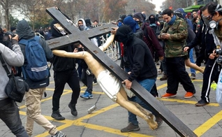 Ao final da marcha, da última quinta-feira, manifestantes mascarados entraram em uma igreja no centro de Santiago e destruíram a cruz 3 de metros de altura, com uma estátua de Jesus Cristo. (Foto: Reuters)