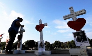 Mulher escreve uma mensagem em uma cruz em honra daqueles que foram mortos na boate gay 'Pulse', em Orlando. (Foto: Reuters)