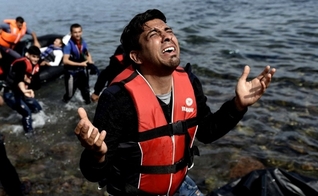 Homem ora após pisar em terra firme na ilha grega de Lesbos, depois de atravessar o mar. (Foto: Aris Messinis/AFP)