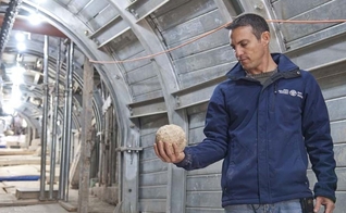 Arqueólogo segura bola de pedra, usada na batalha por Jerusalém, em 70 d.C. (Foto: IAA)