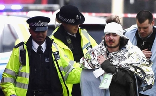 Policiais britânicos socorrem homem ferido em ataque, em Londres. (Foto: El País)