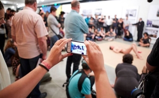 Pessoa filma homem nu, deitado em tablado do Museu de Arte Moderna. (Foto: Divulgação)
