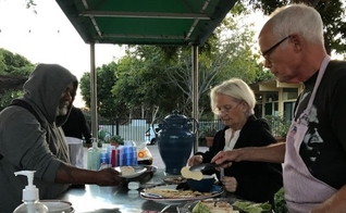 Morador de rua recebe refeição em espaço organizado pela Igreja Metodista Unida, em Malibu. (Foto: Orange County Register)