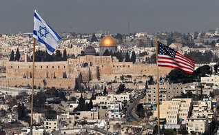Bandeiras de Israel e dos EUA são vistas no telhado de um prédio em Jerusalém Oriental. (Foto: Ahmad Gharabli/AFP)