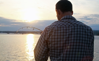 Imagem ilustrativa. Homem de costas para a câmera ajustando sua linha de pesca. (Foto: Nicko Margolies)