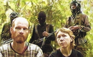 Martin (à direita) e Gracia Burnham (esquerda) com terroristas do Abu Sayaff ao fundo. (Foto: Persecution Blog)