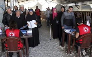 Refugiados sírios recebendo ajuda da agência de refugiados da ONU em Trípoli, no norte do Líbano. (Foto: Reuters/Omar Ibrahim)