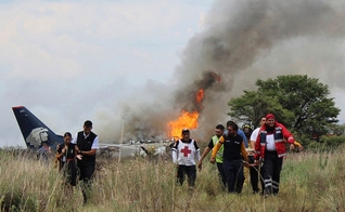 Socorristas carregam ferido em maca durante resgate após acidente com avião da Aeroméxico. (Foto: Red Cross Durango/AP)