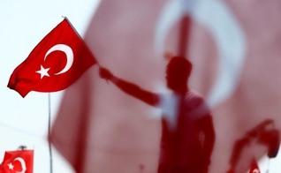 Homem segura bandeira da Turquia durante homenagem aos 'mártires da democracia'. (Foto: Reuters)