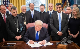 Donald Trump é cercado por líderes religiosos e legisladores no Salão Oval, ao assinar lei de ajuda humanitária. (Foto: Casa Branca/Shealah Craighead)