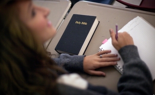 Imagem ilustrativa. Estudante com um exemplar da Bíblia em sua mesa na sala de aula. (Foto: Associated Press/David Goldman)
