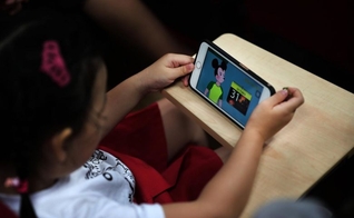 Criança assiste vídeo qualquer do Youtube em smartphone. (Foto: The Straits Times)