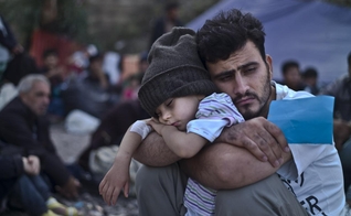 Refugiado sírio segura o filho nos braços em campo, na Turquia. (Foto:  AP/Lefteris Pitarakis)