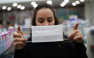 Vendedora mostra máscara de proteção, em Guarulhos (SP), usada diante da epidemia do novo coronavírus pelo mundo. (Foto: Amanda Perobelli/Reuters)