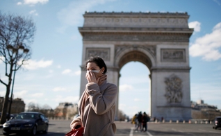 Mulher usa máscara de proteção perto do Arco do Triunfo, em Paris, na França. (Foto: Gonzalo Fuentes/Reuters)