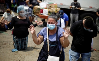 Fornecedores do maior centro de suprimentos de frutas e legumes de San Salvador em momento de oração. (Foto: EFE/Rodrigo Sura)