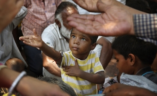 Criança estende a mão para receber comida em Nova Delhi, na Índia. (Foto: AP/Manish Swarup)