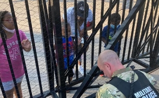 O soldado Dan Otterson (de farda) se ajoelhou, enquanto o garoto de 5 anos orou por ele, do outro lado da cerca. (Foto: Facebook)