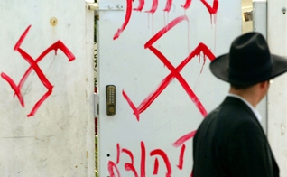 Homem judeu olha para grafite antissemita no portão de uma sinagoga próxima a Tel Aviv, em 2006. (Foto: Uriel Sinai/Getty Images)
