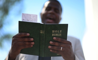 Pastor lê a Bíblia enquanto conduz uma oração, nos EUA. (Foto: Joe Raedle/Getty Images)