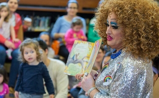 Drag queen conta história para crianças em imagem exibida por propaganda do projeto na TV. (Foto: AP Photo)