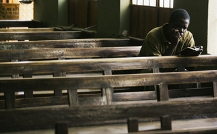 Cristão lê Bíblia sozinho no banco de uma igreja em, Kano, Nigéria. (Foto: Getty Images/Chris Hondros)