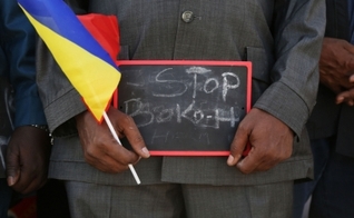 Homem segura uma pequena placa que diz "Pare, Boko Haram", em um evento para apoiar as tropas militares de Chade