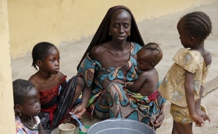 Mulher resgatada dos domínios do Boko Haram pelo exército nigeriano alimenta seus filhos em acampamento para refugiados
