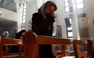 Mulher cristã assíria ora por seus compatriotas sequestrados. (Foto:  REUTERS/OMAR SANADIKI)