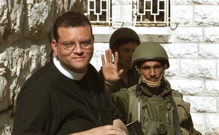 Um soldado israelense (R) recebe o Rev. Andrew White, o "vigário de Bagdá", enquanto ele tenta visita a Igreja da Natividade, em Belém, no dia 14 de abril de 2002. (Foto: Reuters/Oleg Popov)