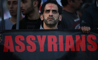 Um homem assírio caminha durante um protesto unido a centenas de pessoas. (Foto: Reprodução/The Wall Street Journal)
