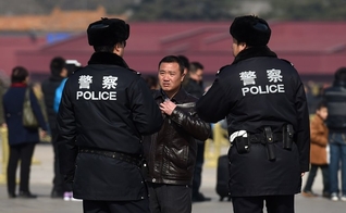 Policiais interrogam um homem na Praça Tiananmen, em Pequim. (Foto: Greg Baker/Agence France-Presse — Getty Images)