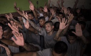 Antigos membros de gangues, presos na cadeia de Gotera, levantam as mãos durante o culto. (Foto: Victor Peña/El Faro)