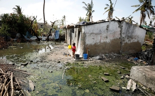 Criança ao lado de poças de água parada em Beira, Moçambique, nesta quarta-feira (27) (Foto: Mike Hutchings/Reuters)