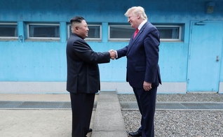 Trump em aperto de mãos com Kim na linha de demarcação que divide as duas Coreias. (Foto: KCNA via Reuters)