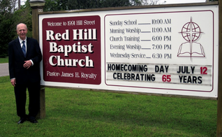 James Royalty ao lado da placa da Igreja com o anúncio de seus 65 anos de pastoreio, em 2015. (Foto: Reprodução/Baptist Red Hill Church)