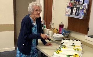 Marion Needham corta o bolo de aniversário preparado em sua homenagem por muitos amigos da igreja para marcar seu 100º aniversário. (Foto: Reprodução/Barnabas Fund)