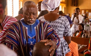 O Taraana, um dos sete anciãos do chefe supremo, ora sobre seus colegas diáconos durante a ordenação deles na Primeira Igreja Batista, Nalerigu. (Foto: Reprodução/IMB)
