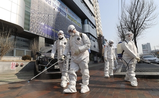 Trabalhadores com equipamento protetor usam desinfetante em spray contra o novo coronavírus em frente à igreja em Daegu, na Coreia do Sul, nesta quinta-feira (20). (Foto: Kim Jun-beom/Yonhap via AP)