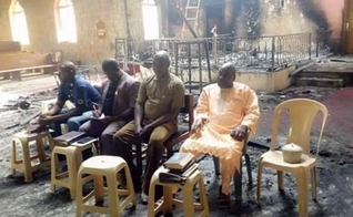 Os anciãos da igreja nigeriana realizam o culto de domingo em meio às cinzas de sua igreja incendiada apenas dois dias após um devastador ataque ao Boko Haram. (Foto: Reprodução / Barnabas)