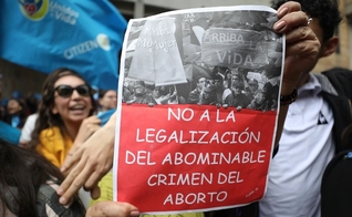 Um ativista antiaborto segura uma placa que diz em espanhol "Não à legalização do crime abominável do aborto", durante um protesto em frente ao tribunal constitucional da Colômbia em Bogotá, em 2 de março. (Foto: Fernando Vergara / AP)