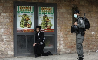 Policial israelense detém um judeu ultraortodoxo durante patrulha em Jerusalém. (Foto: Reprodução/AFP)